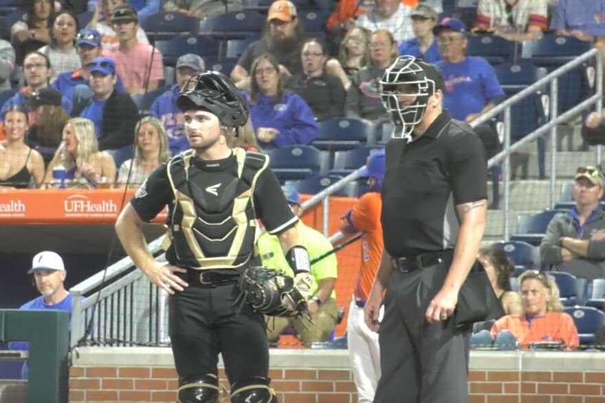 Neri stands with the umpire, awaiting the next play before putting his mask back on as the batter walks to the plate. (Kathryn Ross/WUFT News)