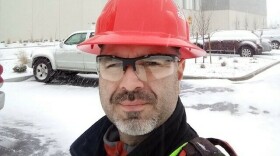 James Lopez stands in front of an Amazon building he helped construct in Washington state. Lopez has suspended a months-long housing search because his family can't afford to keep paying hundreds of dollars in rental application fees.