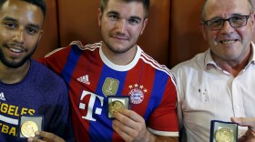 Three men who helped to disarm an attacker on a train from Amsterdam to France, from left to right, Anthony Sadler, Alek Skarlatos and Chris Norman, a British man living in France, pose with medals they received for their bravery at a restaurant in Arras, France. A fourth man, American Spencer Stone, was wounded in the take-down and remains in the hospital.