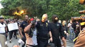 IMPD Lt. Andrew Rolinson and one of the march leaders, Malik Muhammad, walk south down Meridian Street, away from the governor's residence.