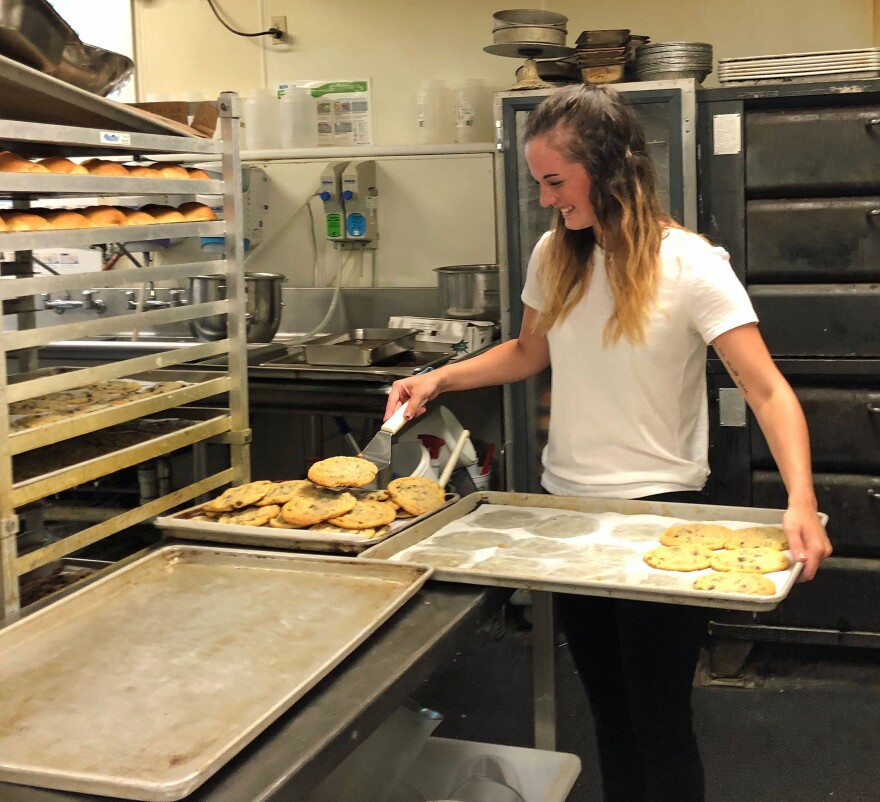 Wayside employee Nicole Furman takes freshly baked cookies off of a sheet pan in the Wayside's backroom bakery.