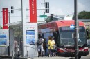 Exterior photo of a red transit bus stopped at a bus stop labeled "Prospect at 31st." People can be seen getting off the bus while others are waiting to get on.