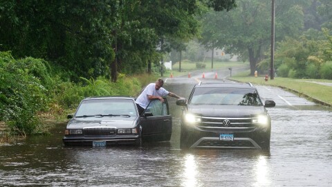 FILE: Jacob Tebecio climbs from his friend's car into his own which was stuck thanks flooding caused by tropical storm Henri June 22, 2021.