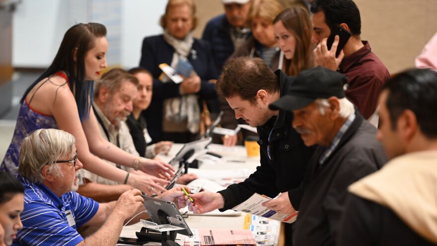 Poll workers (left) assist voters (right) waiting in line to cast their ballot during the presidential primary vote in Glendale, Calif. on Tuesday.
