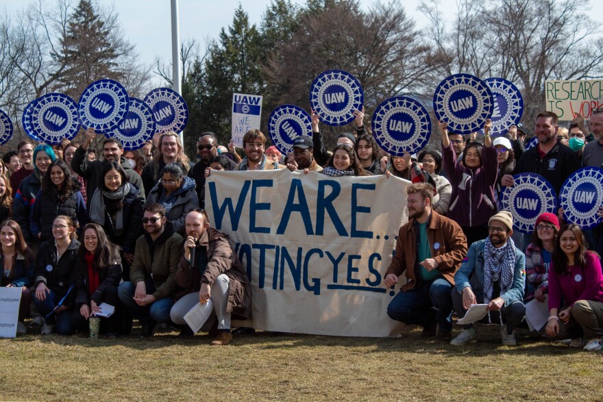 Graduate student workers hold signs calling for the university to allow a union vote.