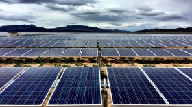 A large solar farm, with solar panels stretching out in the distance towards far-away mountains.