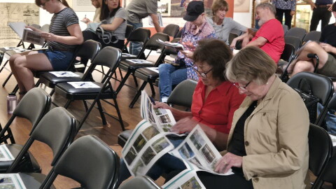 Two women discuss renders as people find their seats at the Matheson History Museum on Sept. 29. The packets include design options for the future site.