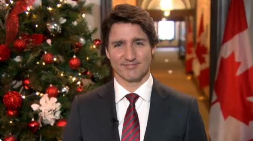 Canadian Prime Minister Justin Trudeau in front of a Christmas tree and Canadian flag