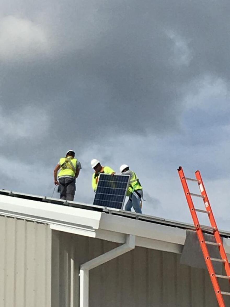 Workers install solar panels on a new city building, part of Georgetown's holistic approach to renewables.