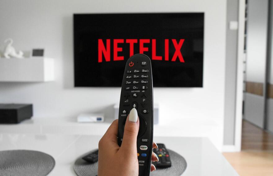 netflix on a tv screen. hand holds remote.