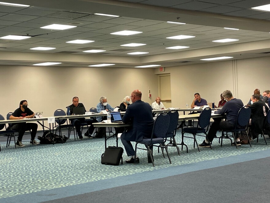 Commission members gather around tables in a conference room