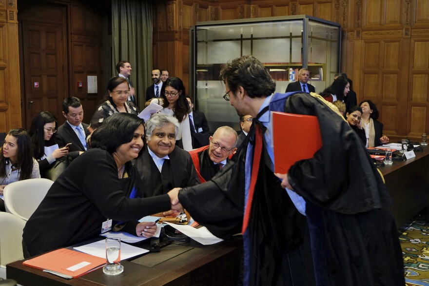 Members of the Indian delegation to the International Court of Justice, Neeru Chadha (left) and Harish Salve (center), greet a member of the Marshall Islands' legal team ahead of a preliminary hearing on nuclear disarmament at the International Court of Justice.