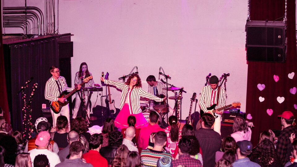 A crowd of people watch the band Ramona and the Sometimes perform at xBk Live in coordinating striped shirts.