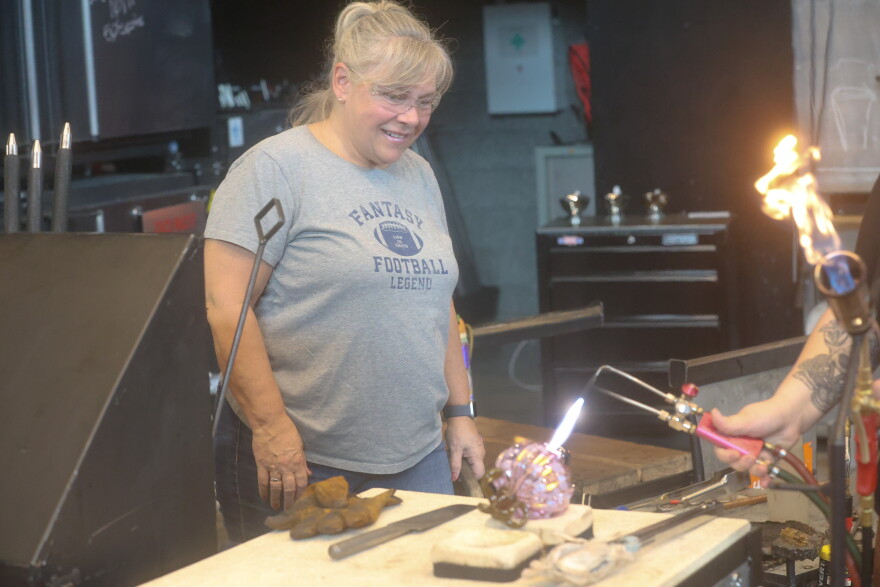 Norfolk resident Margaret Gemski watches as the final touches are applied to the pumpkin she created from glass.