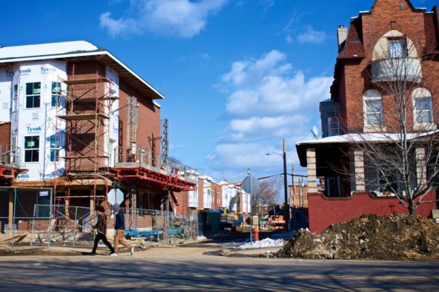 Two young men walk past a rehab project in Strawberry Mansion. (Bastiaan Slabbers for WHYY)