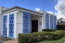 A white building decorated with blue stars of david at the entryways. A shadow is by the front door where a plaque once was.
