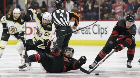 Boston Bruins' Sean Kuraly (52) and Carolina Hurricanes' Greg McKegg struggle during a face-off while Hurricanes' Brock McGinn (23) grabs the puck during the first period in Game 4 of the NHL hockey Stanley Cup Eastern Conference final series in Raleigh, 