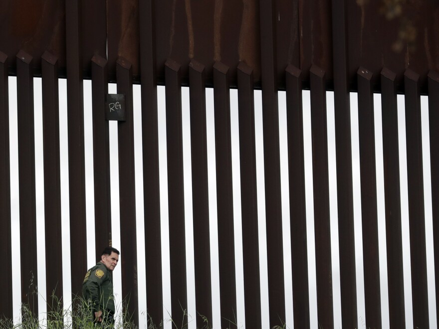 A border patrol agent walks along a border wall separating Tijuana, Mexico, from San Diego in March. The Trump Administration has proposed a number of changes that would restrict asylum claims.