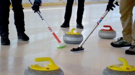 Brooms sweep ahead of a stone as it glides towards the house.