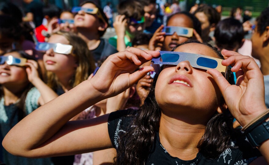 Pupils, wearing protective glasses, look at the partial solar eclipse in Schiedam, Netherlands, on Thursday.