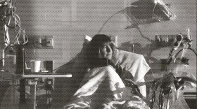 A woman in a hospital bed gazes to her left.