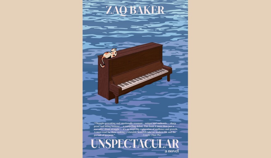 Cover of "Unspectacular" by Zaq Baker; illustration of an upright piano partially submerged in water with a cat laying on top