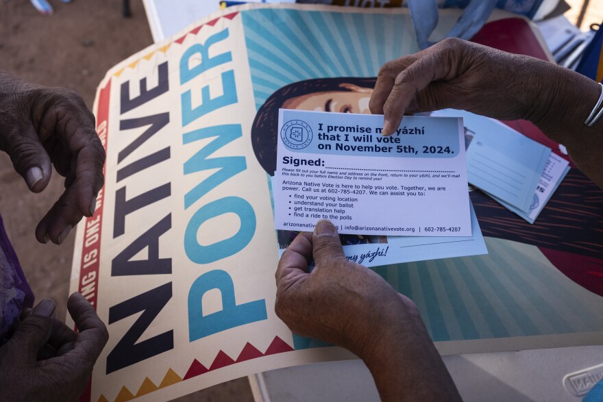 FILE - Local organizer Maria Calamity instructs a resident on how to properly fill out a pledge card promising to vote in the upcoming presidential election on the Navajo Nation in Ganado, Ariz., Oct. 11, 2024. (AP Photo/Rodrigo Abd, File)