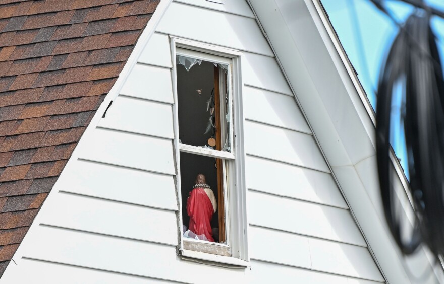 A statue and dream catchers still stand in a broken window of 77 South Grant Street where a fatal fire occurred Monday.
