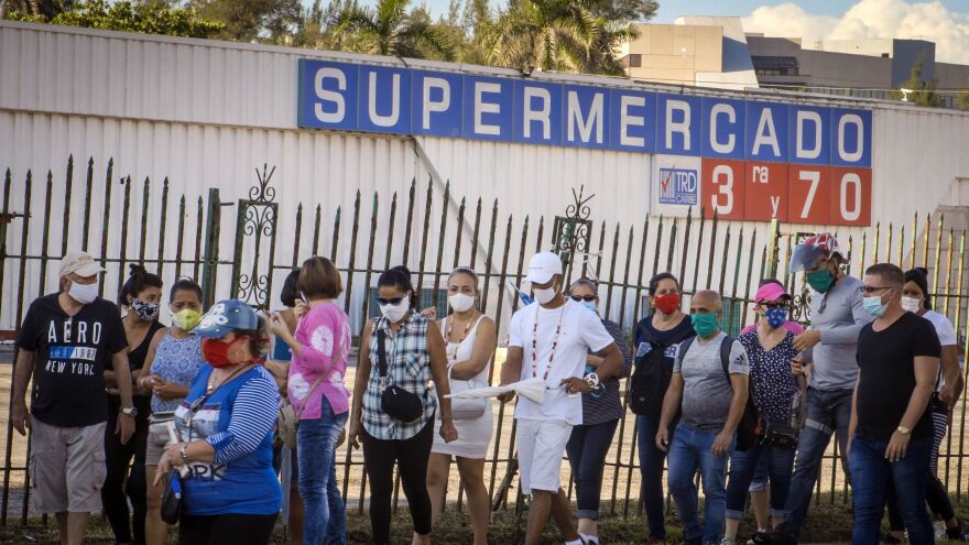 People wait to buy products with U.S. dollars at a supermarket in Havana on July 20. Cuba has eliminated a tax on dollars and opened "dollar stores" in an attempt to boost the economy.