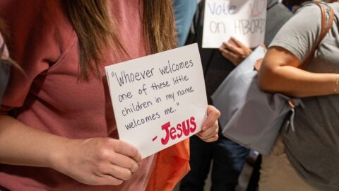Outside a House subcommittee, a woman holds a sign quoting scripture in protest of immigration legislation. 