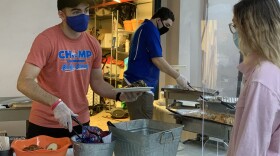 Hillel volunteers serve a kosher meal from Gil’s Kitchen to a student. Directors allowed tables to go up for food one-by-one to prevent crowding in the line, and they could only take off their masks once they were sitting down and physically eating. (Ava Loomar/WUFT News)