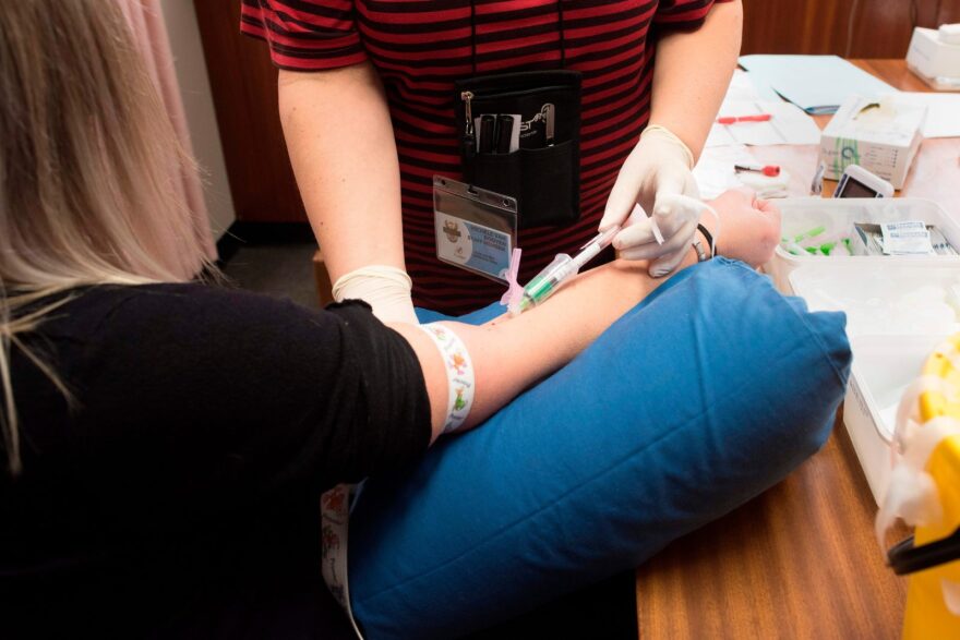 A staff member (R) draws a blood sample from a volunteer at the start of a clinical trial being set up in Cape Town, to see whether the a vaccine given to babies in the country to protect them against tuberculosis, helps limit the damage caused by COVID-19.