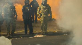 Federal police walk through tear gas while dispersing a crowd of about a thousand protesters at the Mark O. Hatfield U.S. Courthouse in Portland, Ore.