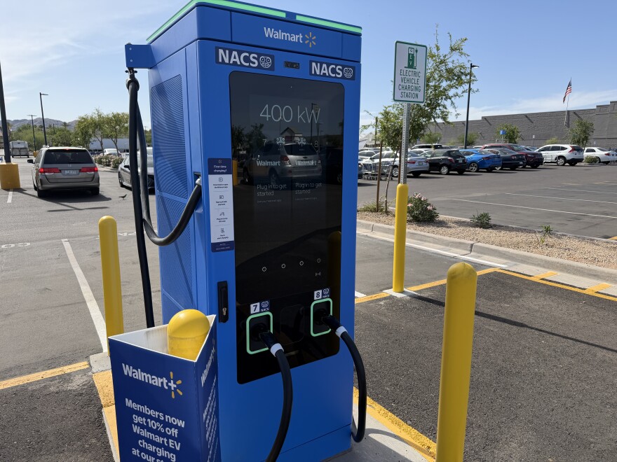 This is a close-up, front-facing view of the same bright blue Walmart electric vehicle charging station. The image provides a detailed look at the user interface and hardware, including two Tesla-style NACS charging handles
