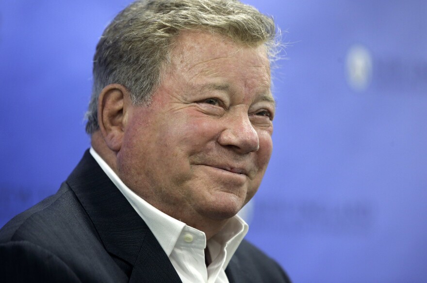 FILE - In this May 6, 2018 file photo, actor William Shatner takes questions from reporters after delivering the commencement address at New England Institute of Technology graduation ceremonies, in Providence, R.I. Star Trek’s Captain Kirk is rocketing into space this month — boldly going where no other sci-fi actors have gone. Jeff Bezos’ space travel company, Blue Origin, announced Monday, Oct. 4, 2021 that Shatner will blast off from West Texas on Oct. 12.