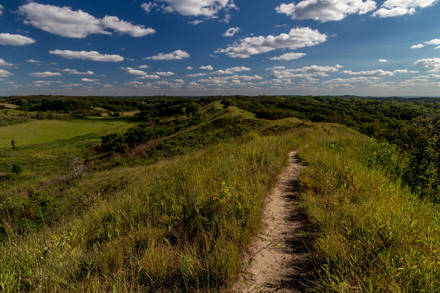 The Loess Hills are shown with green grass and a blue sky.