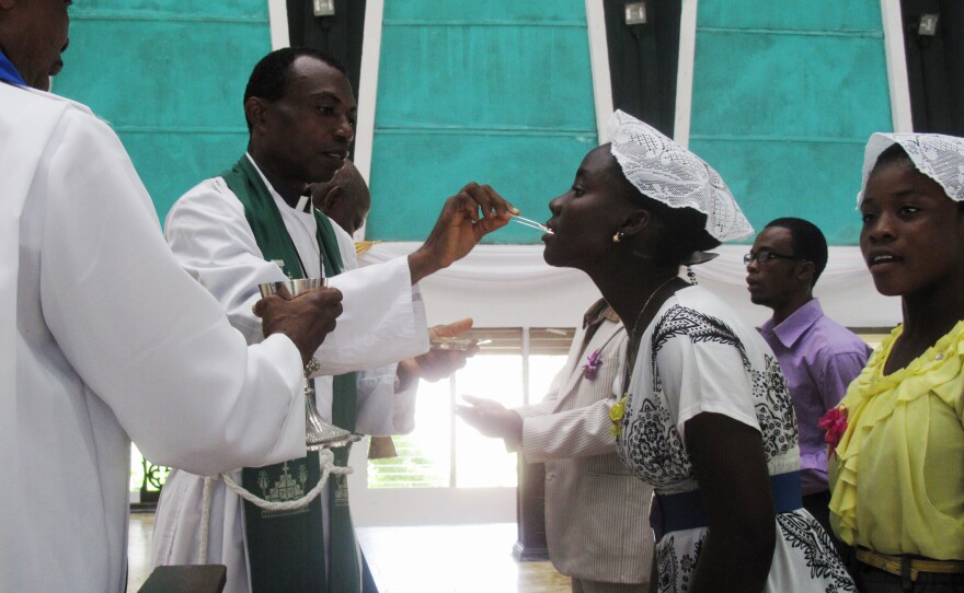 Priests use tweezers to deliver the Holy Communion wafer at Trinity Cathedral in Monrovia to prevent the spread of Ebola.