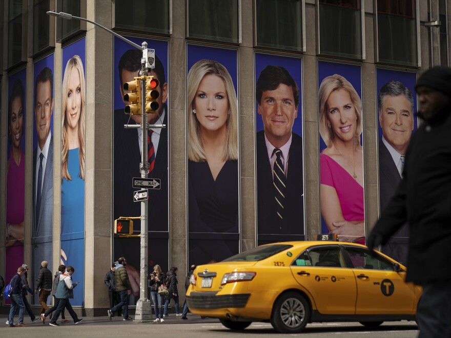 Advertisements featuring Fox News personalities, including Tucker Carlson, adorn the front of the News Corporation building in a 2019 file photo. The cable channel faces a defamation suit going to trial next week based on lies it aired about Dominion Voting System's role in the 2020 election.