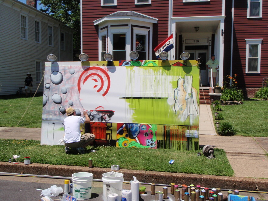 John Romang works on a mural at the festival.