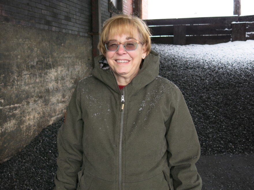 Kelly Brown stands in front of a pile of coal. Her family's business, F.M. Brown's Sons, has sold coal for nearly a century.