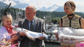 Alaska Governor Bill Walker and First Lady Donna Walker receive a coho, prepared by Colette Nelson of Ludvig’s Bistro and presented by Gavi Stromer in a salmon-bone dress made by Cynthia Gibson. The salmon-themed celebration was organized by local fisherman and organizations. (Emily Kwong/KCAW photo)