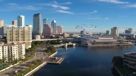 Rendering shows what looks like a helicopter flying over a river toward a city skyline