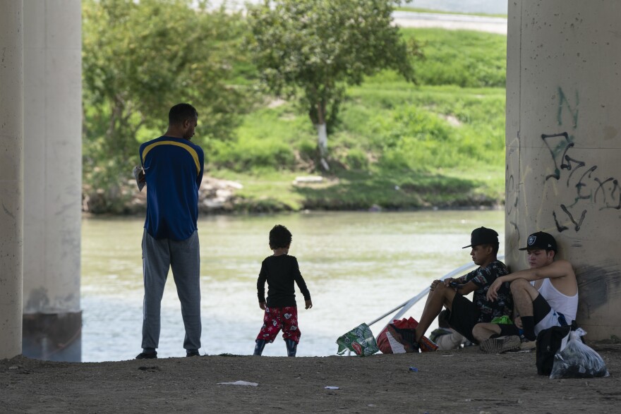Migrants waiting to be picked up by the U.S. Border Patrol under an international bridge in Eagle Pass, Texas, earlier this month. [ Verónica G. Cárdenas for NPR]