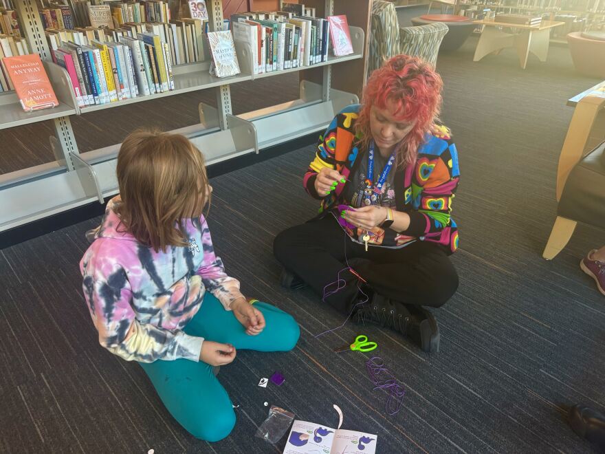 Red Millberry helps a patron get started on a purple dinosaur. Millberry runs the youth services program at the Glenwood Springs branch library.