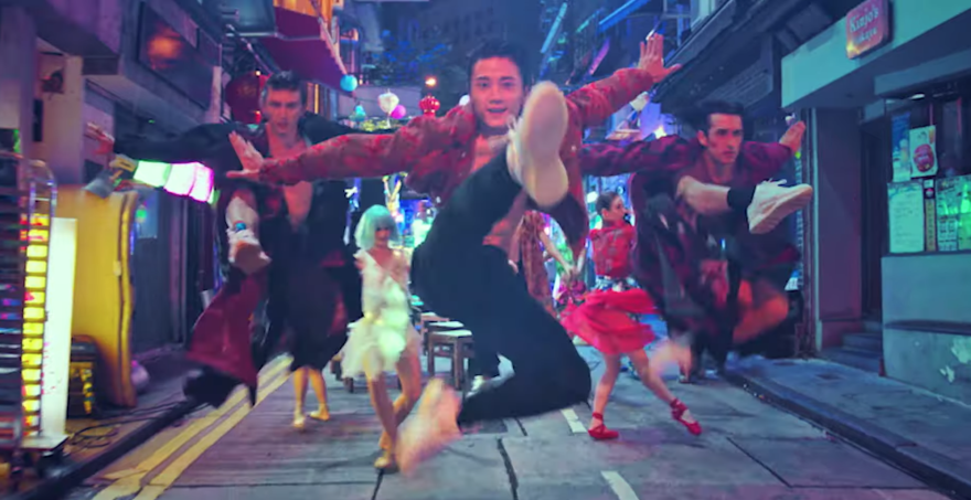 Dancers in bright colors jump while facing the camera