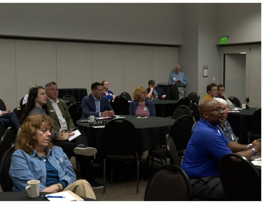 Heading Home attendees sit at black tables at the Bloomington Convention Center. 