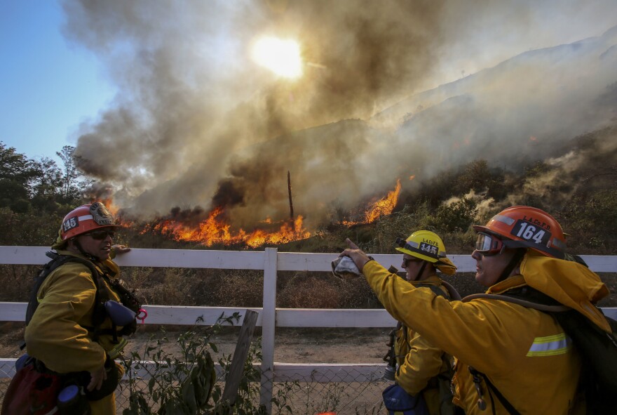 Firefighters watch a blaze in Azusa on Monday. New wildfires erupted Monday near Los Angeles and chased people from their suburban homes as an intense heat wave stretching from the West Coast to New Mexico blistered the region.