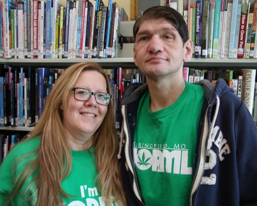 Kimberly Ruiz, left, stands over a head lower than her partner, Lonnie Kessler, right. She wears dark, black-rimmed glasses, they both wear bright green NORML shirts and smile into the camera.  