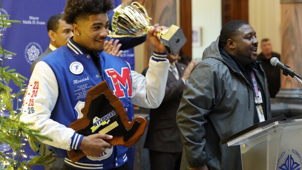 Monroe High School Red Jacket Messiah Hampton holds up the Mayor’s Cup during a formal recognition ceremony at City Hall, where Mayor Malik Evans honored the football team with certificates. The Red Jackets made RCSD history by winning the state championship with a 34–0 victory over Sleepy Hollow, completing a perfect 12–0 season.