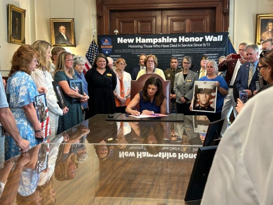 Governor Kelly Ayotte is surrounded by Stephanie Ouellette (left) and Charlene Marois (right) along other gold star advocates as she signs a bill providing Gold Star families special license plates.